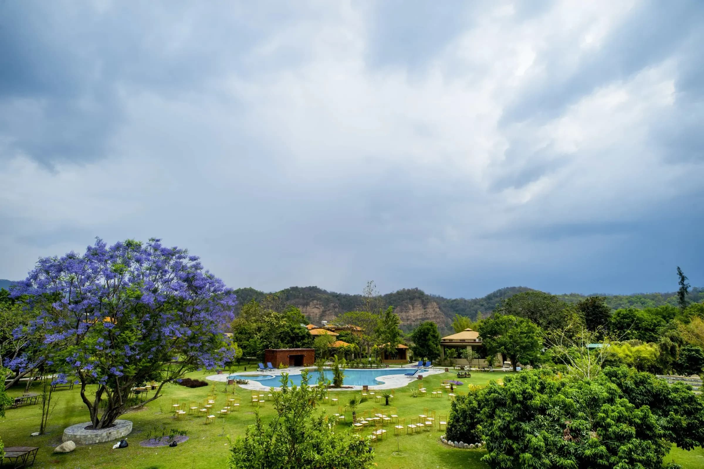 The pool at Tarangi Resort with forested hills behind it, under a stormy sky
