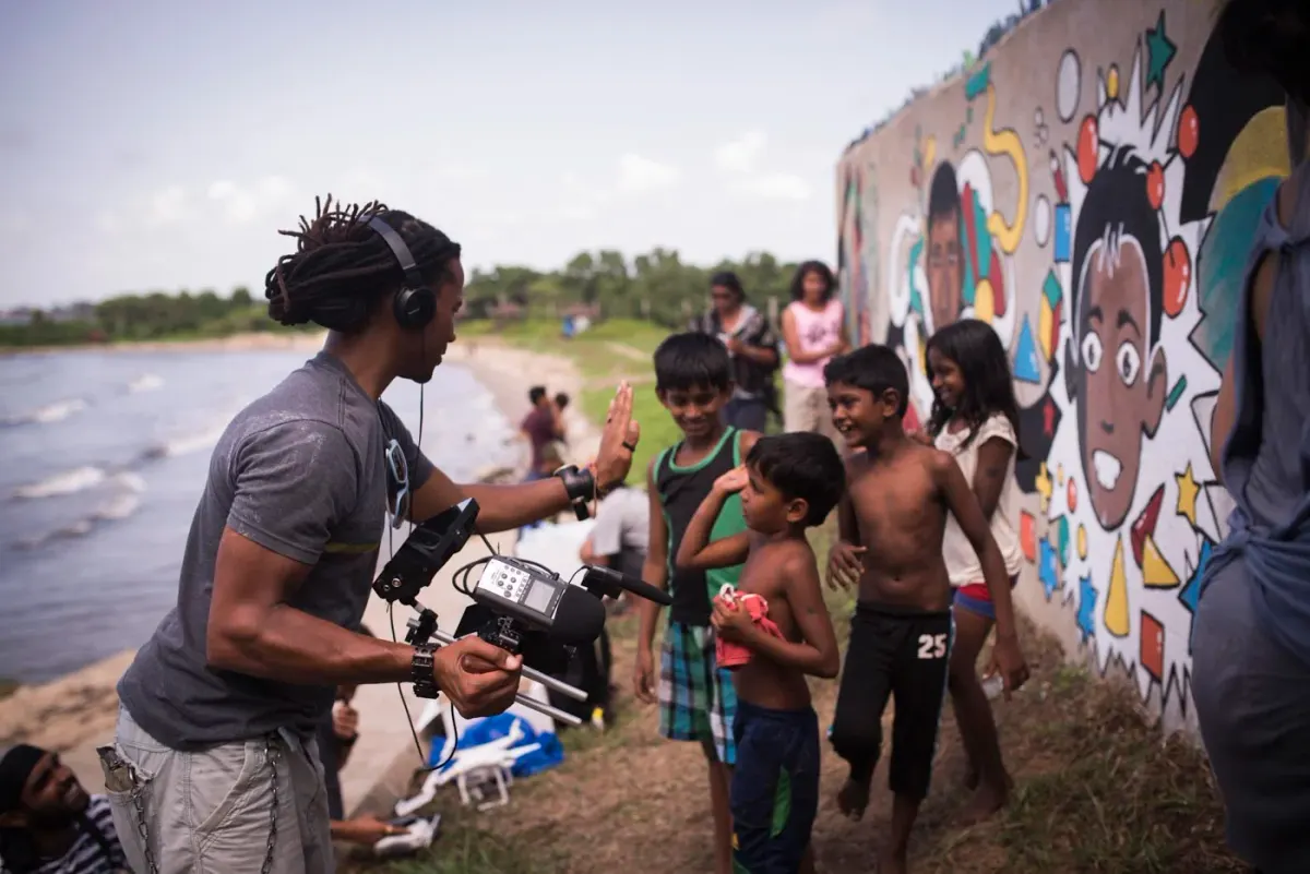 Creators painting a colourful mural on a sea wall with local kids in Sri Lanka