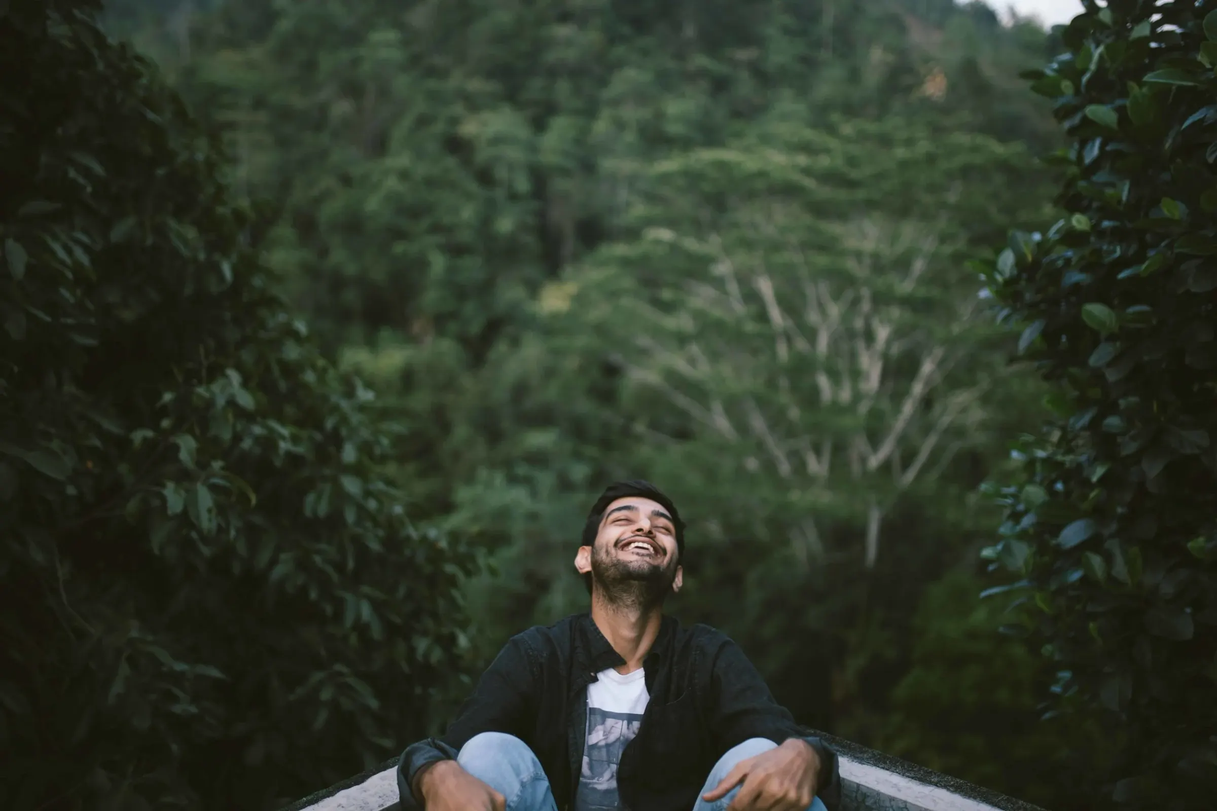 A creator leaning back on a boat looking up into the forest canopy over the Dawki river, Meghalaya