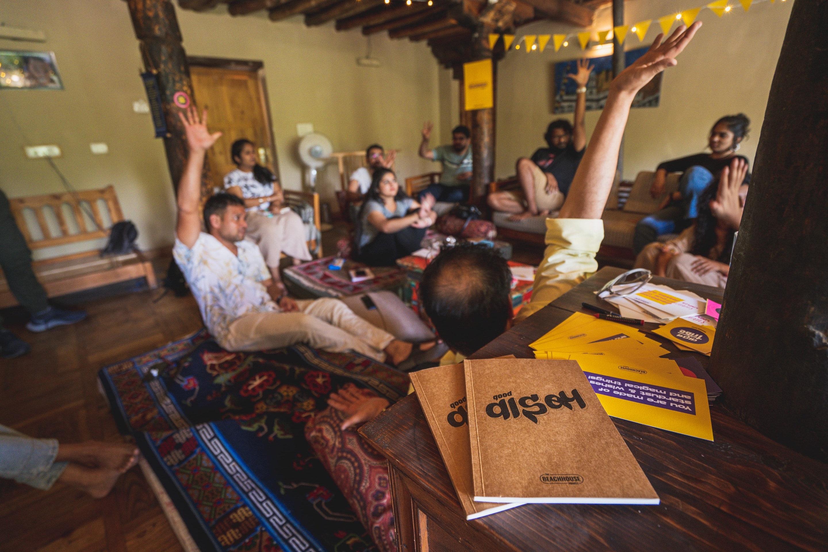 An ExCo group mid-session in a mountain house, hands raised, notebooks on the table