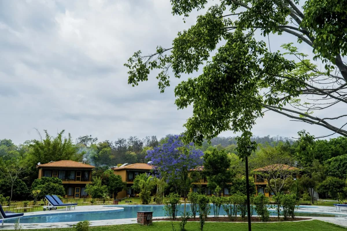 Cottages at Tarangi Resort seen from the pool, under a cloudy sky