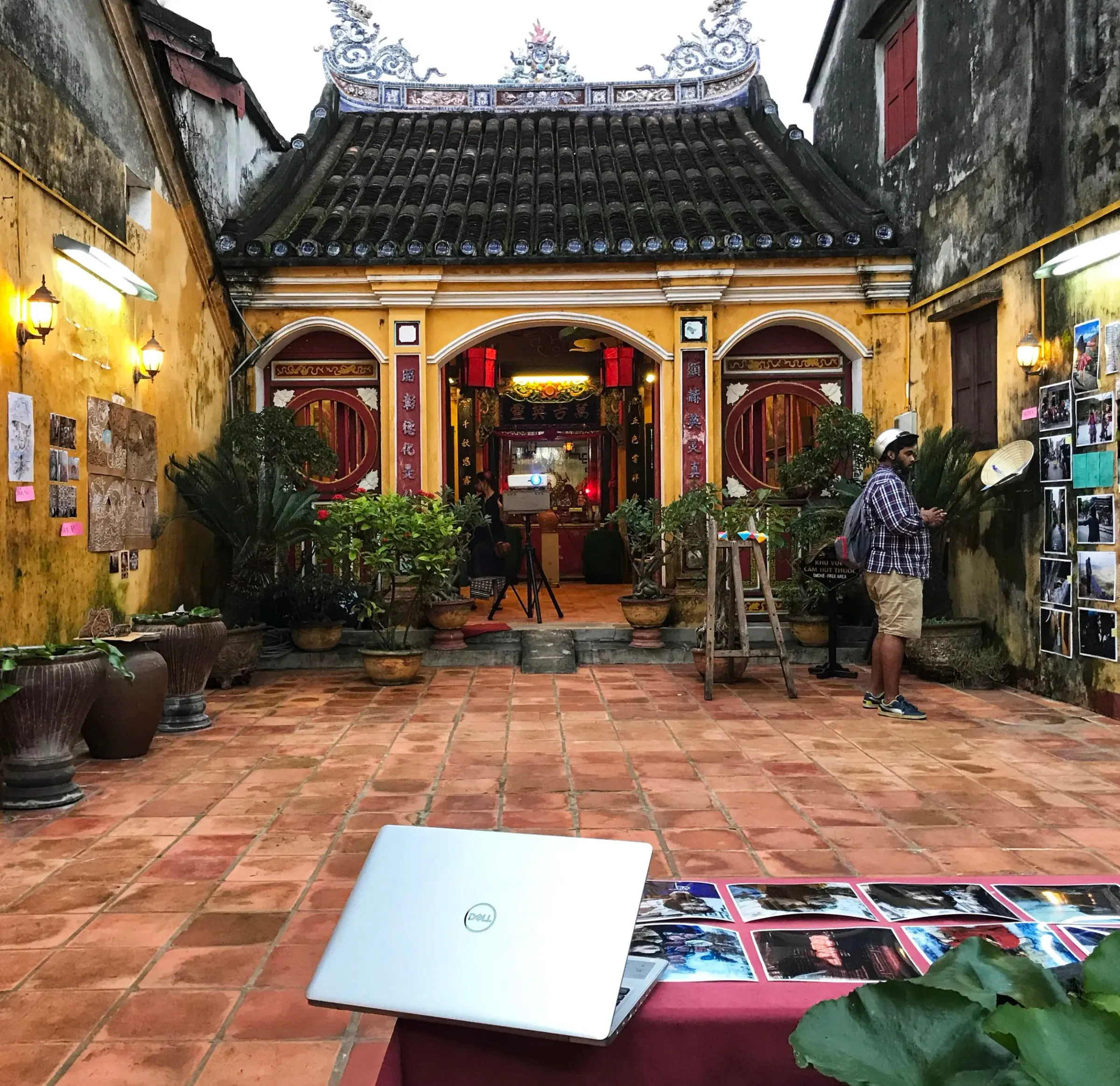 Creators hanging a wall of photo prints on a yellow heritage building in Hoi An, Vietnam